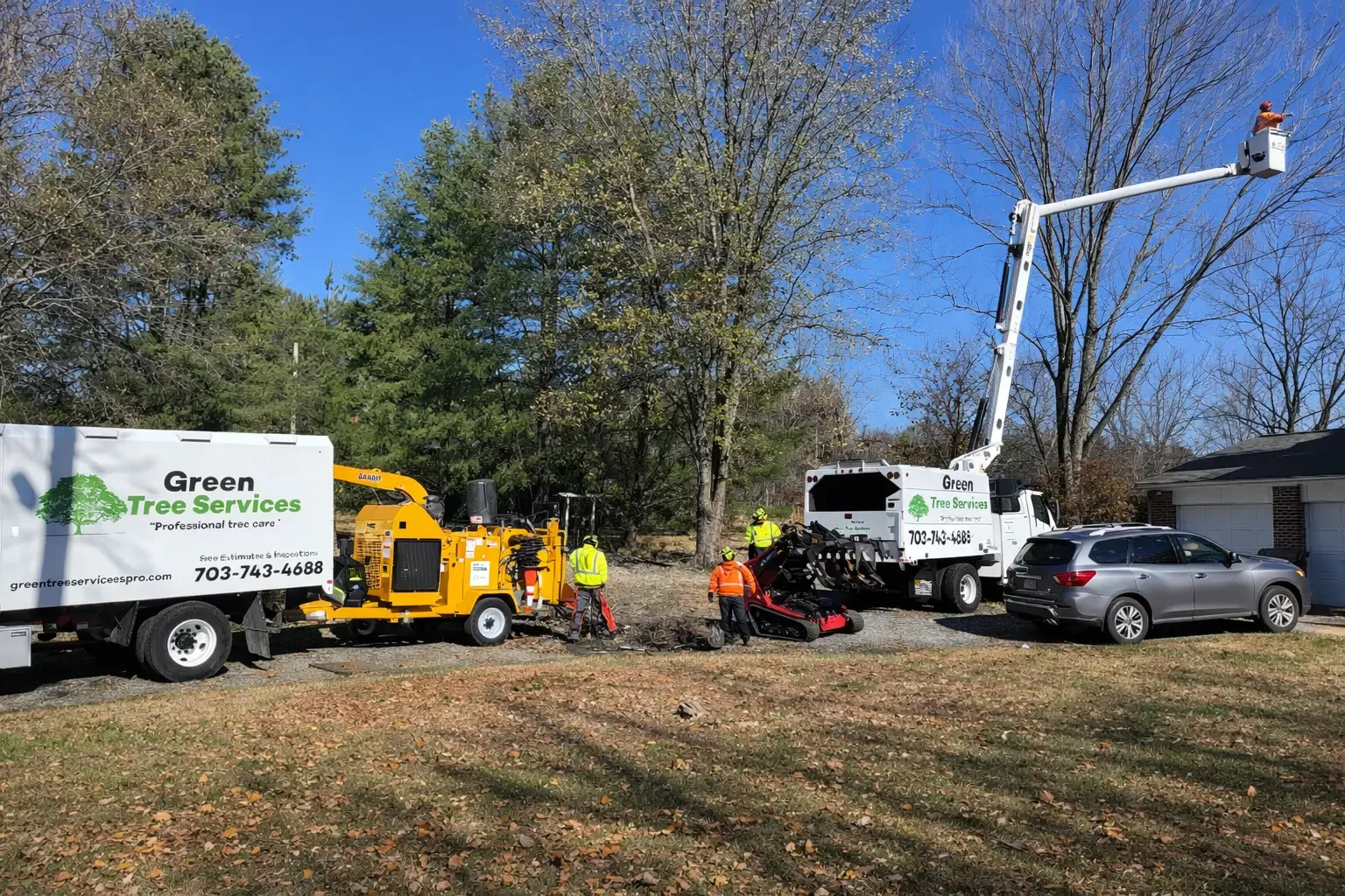 Green Tree Services trucks, chipper and bucket truck on a residential job